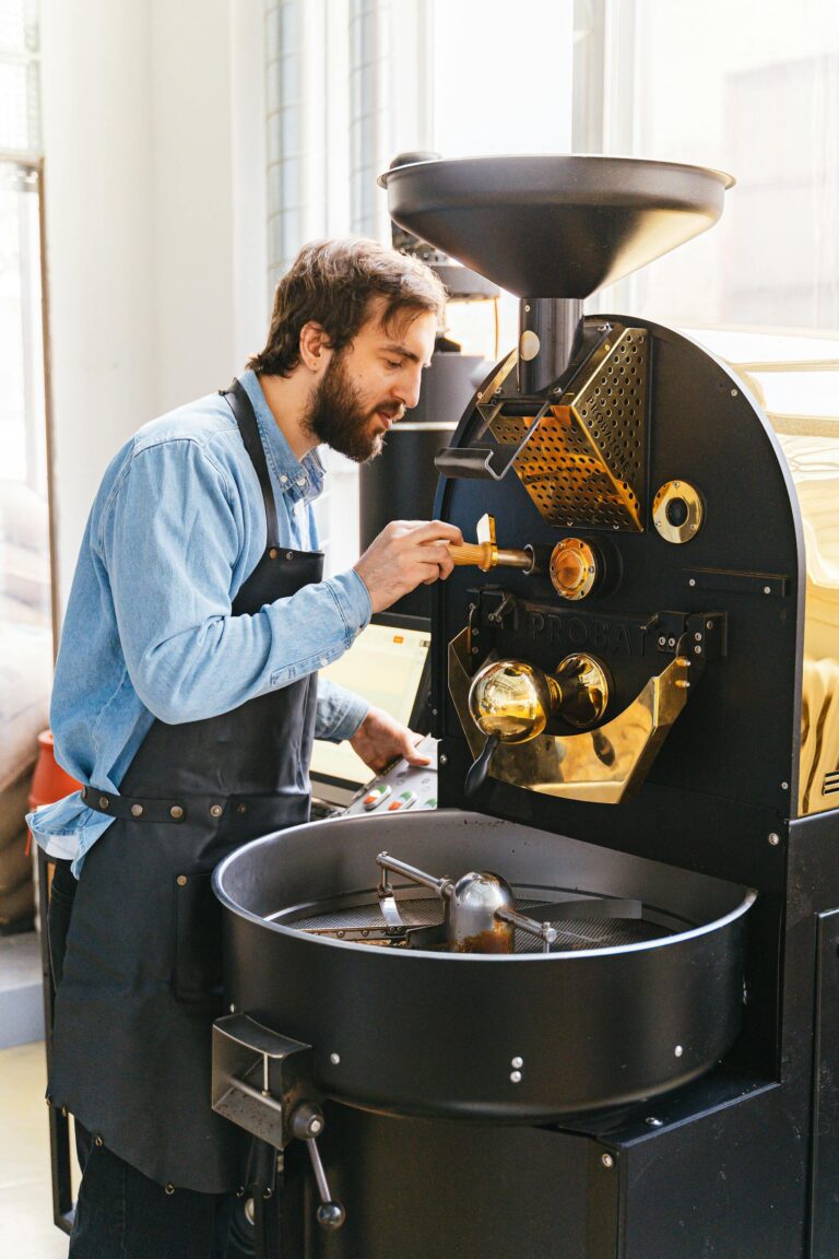 About us 1 Professional barista carefully working with industrial coffee roaster indoors.